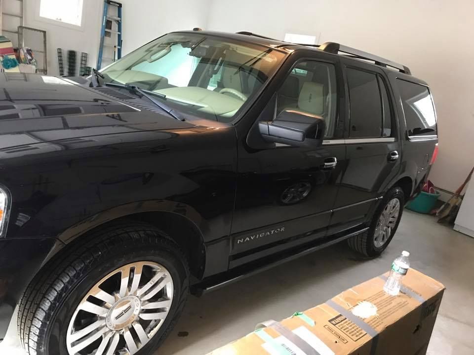 A black suv is parked in a garage next to a cardboard box.