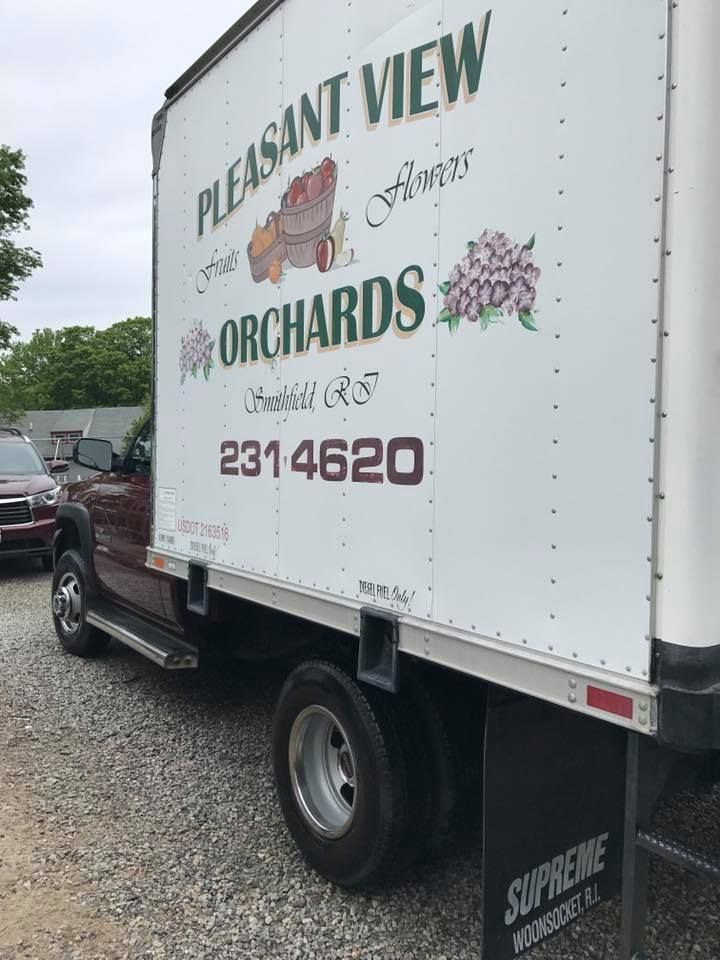 A pleasant view orchards truck is parked in a gravel lot