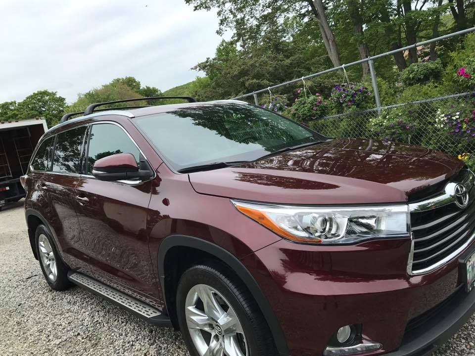 A red toyota highlander is parked in a gravel lot.