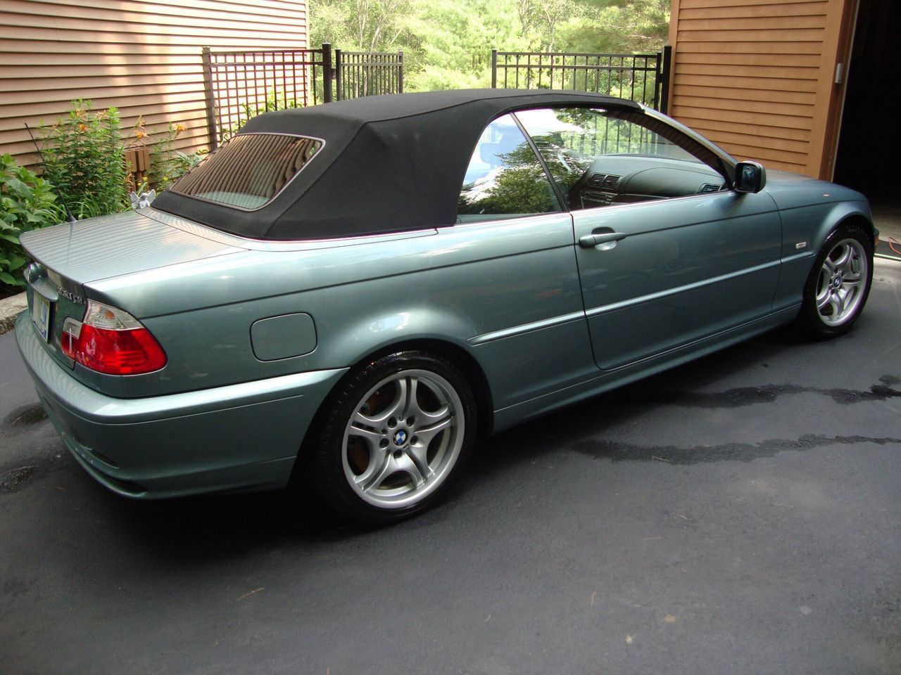 A blue bmw convertible with a black top is parked in a driveway