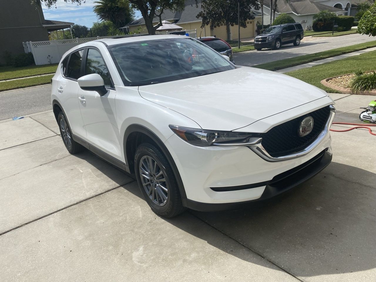 A white mazda cx-5 is parked in a driveway.