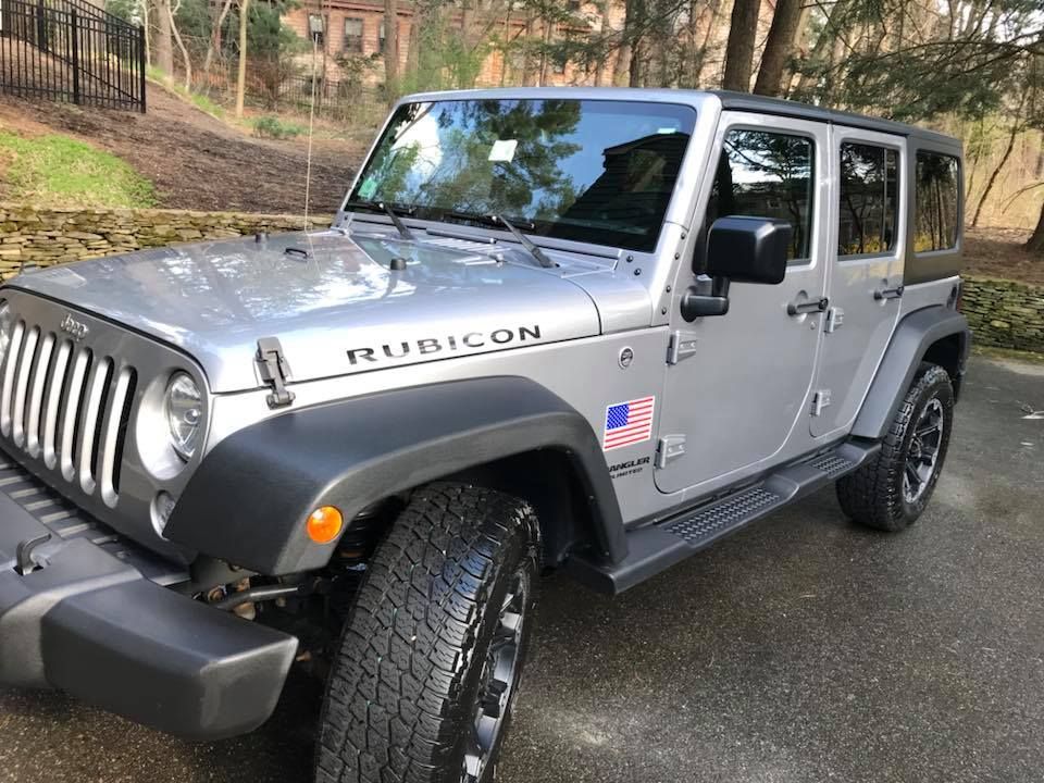 A silver jeep rubicon is parked in a driveway.