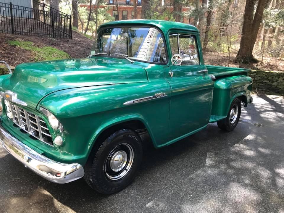 A green pickup truck is parked on the side of the road.