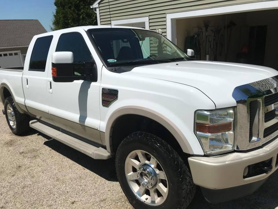 A white pickup truck is parked in front of a garage.