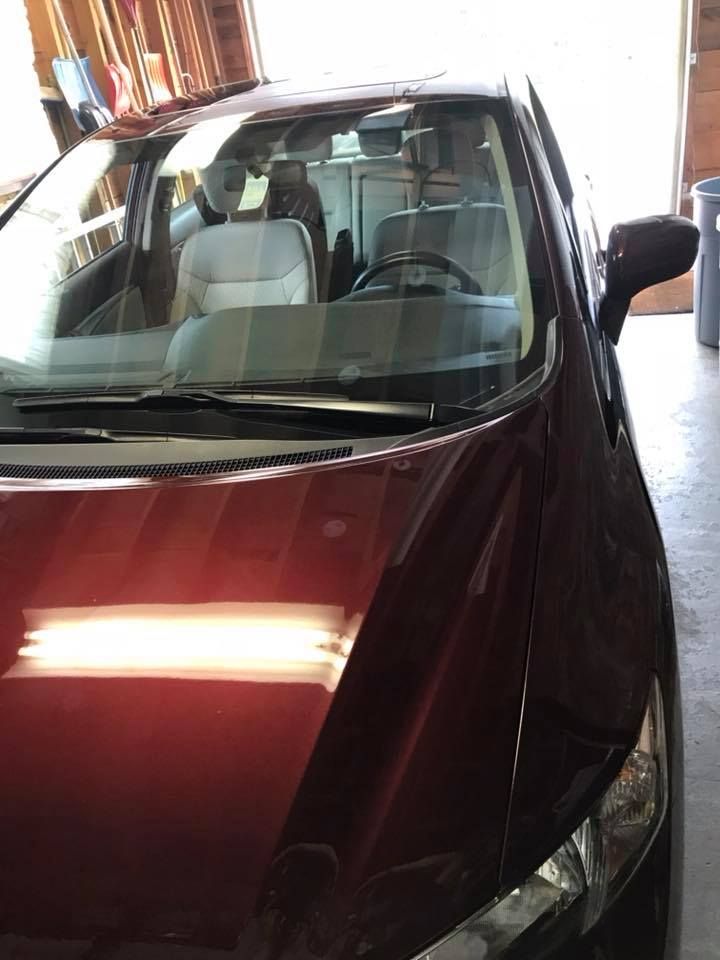 A red car is parked in a garage with the hood up