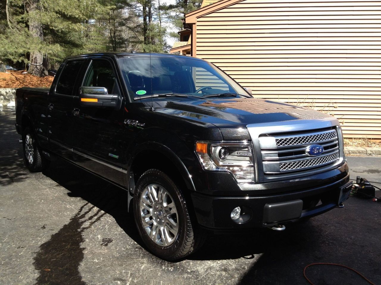 A black ford truck is parked in front of a garage.