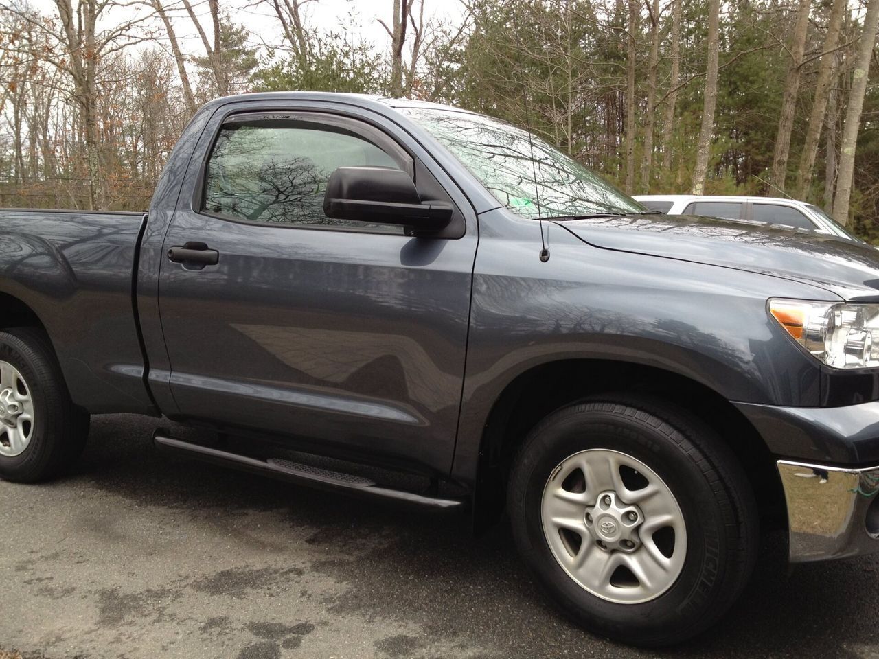 A gray truck is parked on the side of the road
