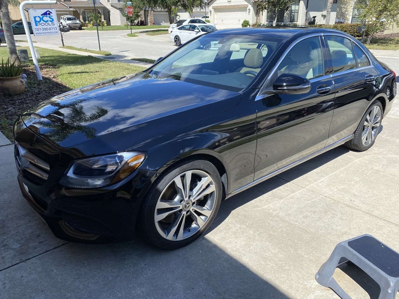 A black mercedes benz c class is parked on the side of the road.