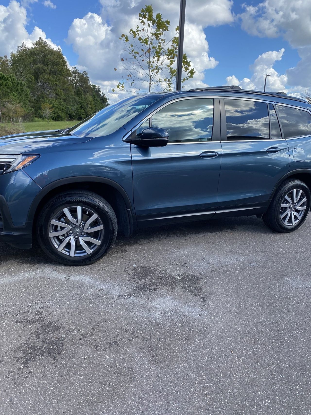 A blue honda pilot is parked in a parking lot.