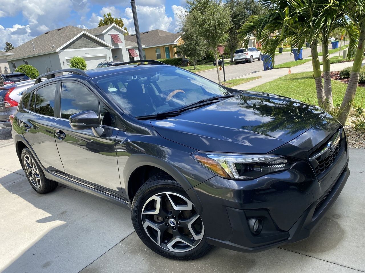 A black subaru crosstrek is parked in a driveway in front of a house.