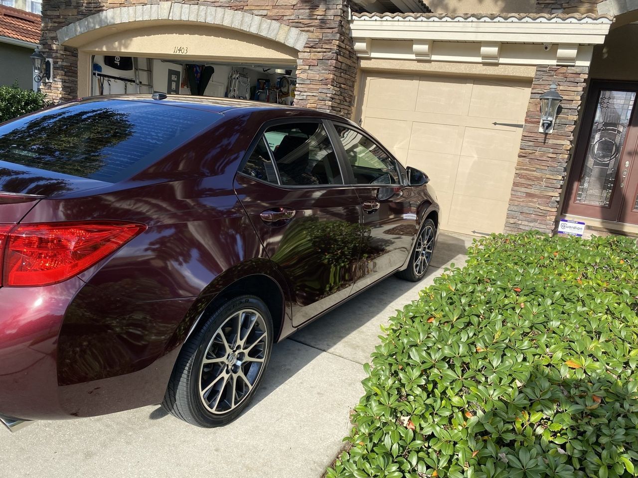 A burgundy car is parked in front of a house.