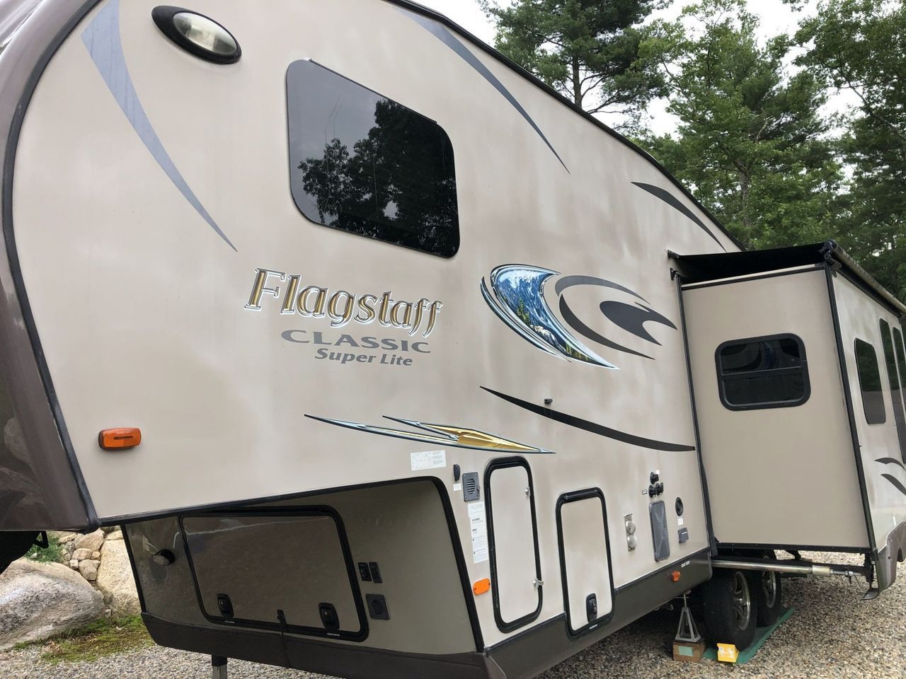 A rv parked in a gravel area with the door open