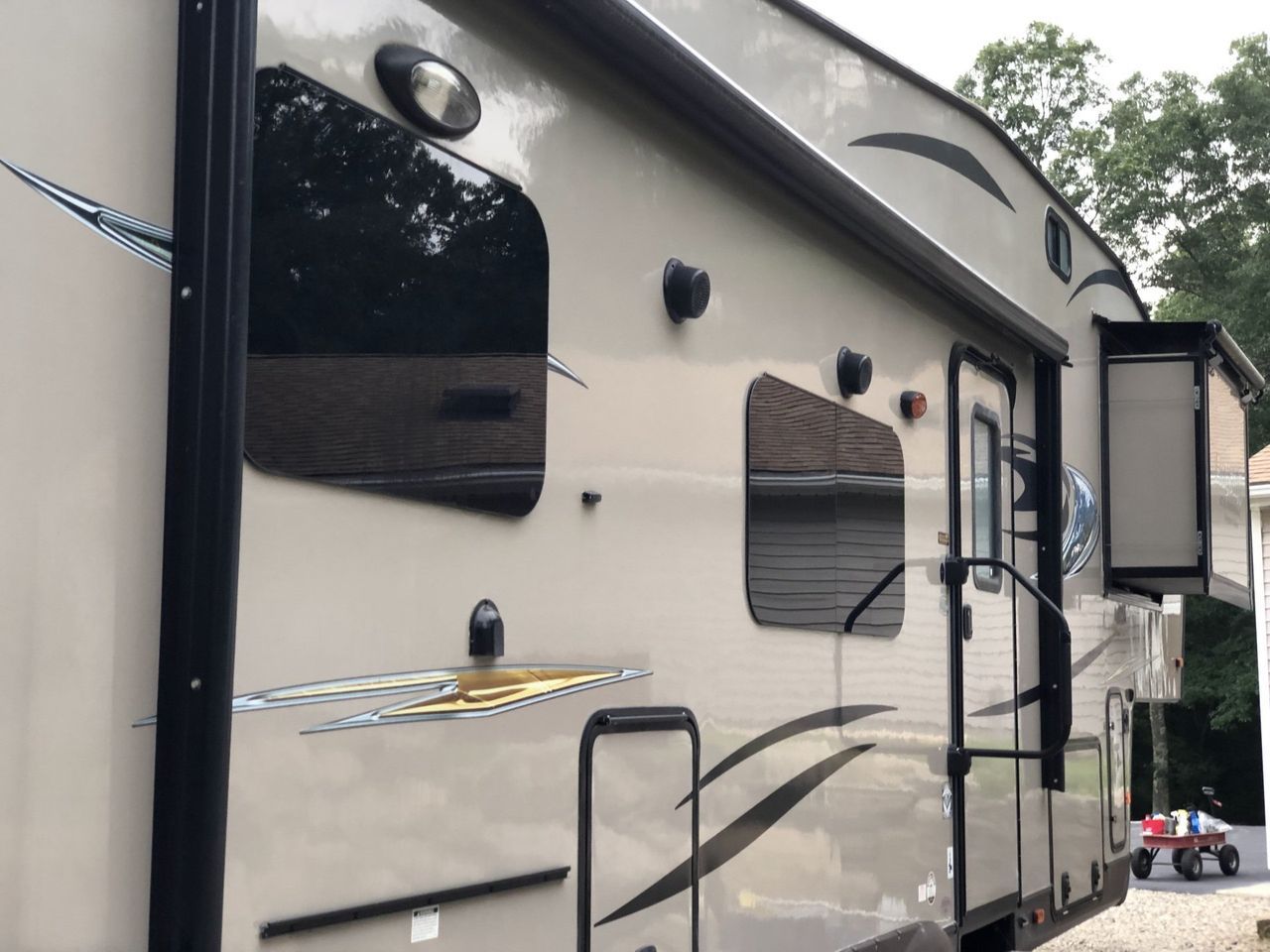 A rv is parked in a driveway next to a red wagon