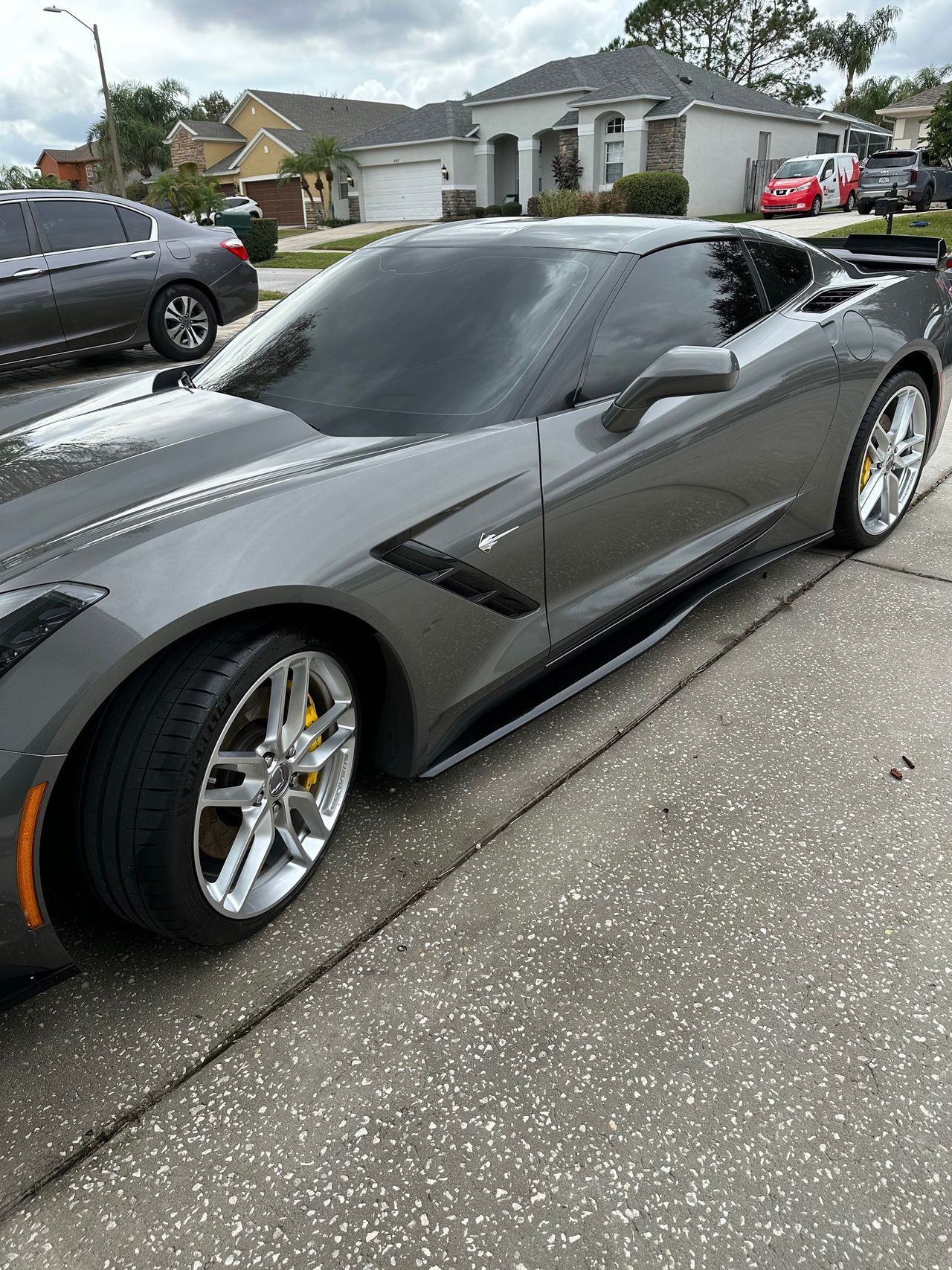 A gray sports car is parked on the side of the road.