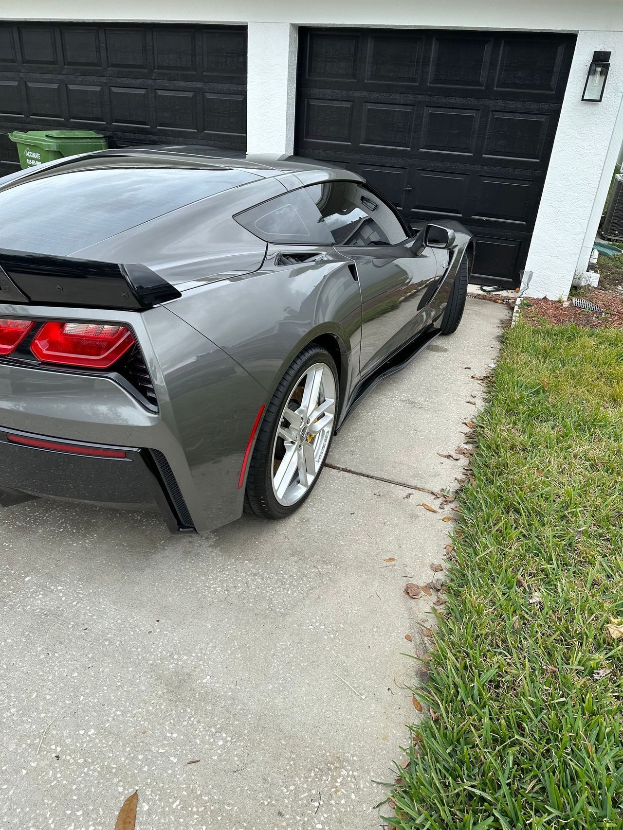 A gray sports car is parked in front of a garage door.