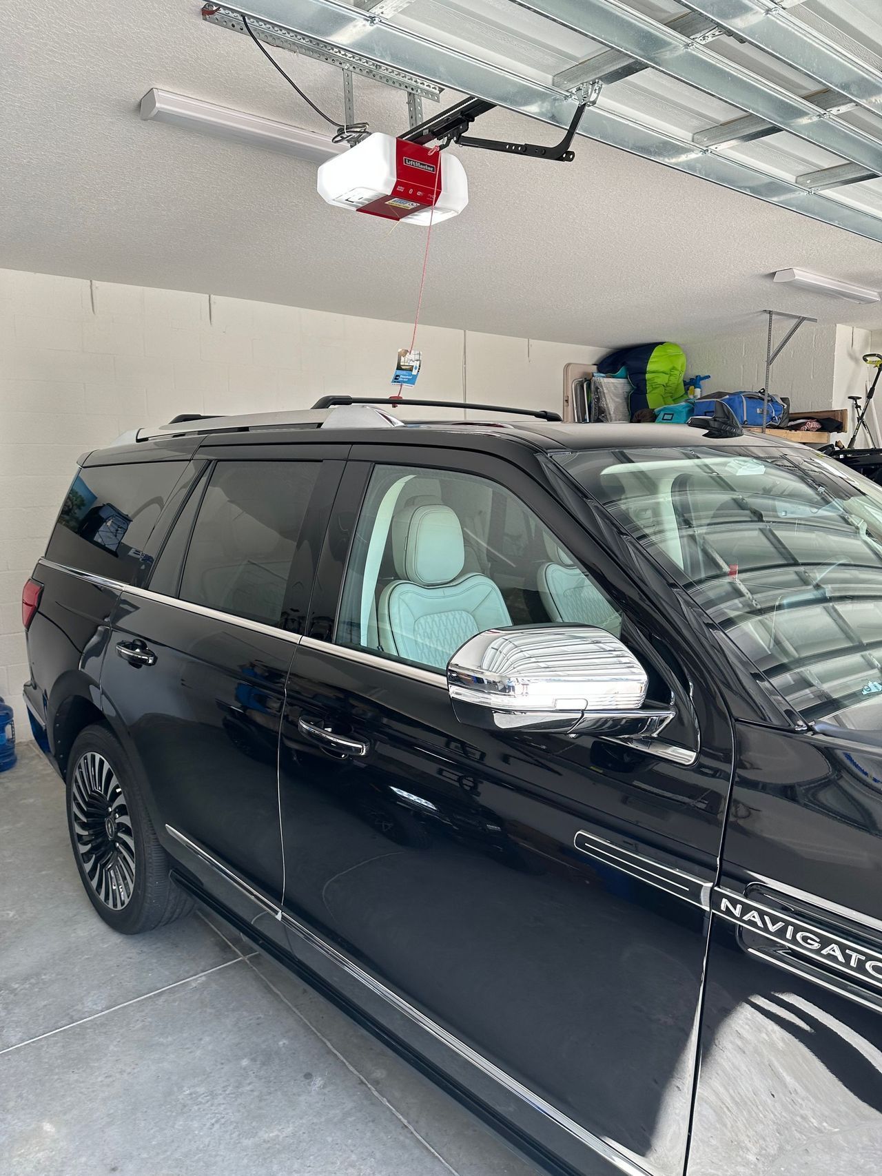 A black suv is parked in a garage under a garage door opener.