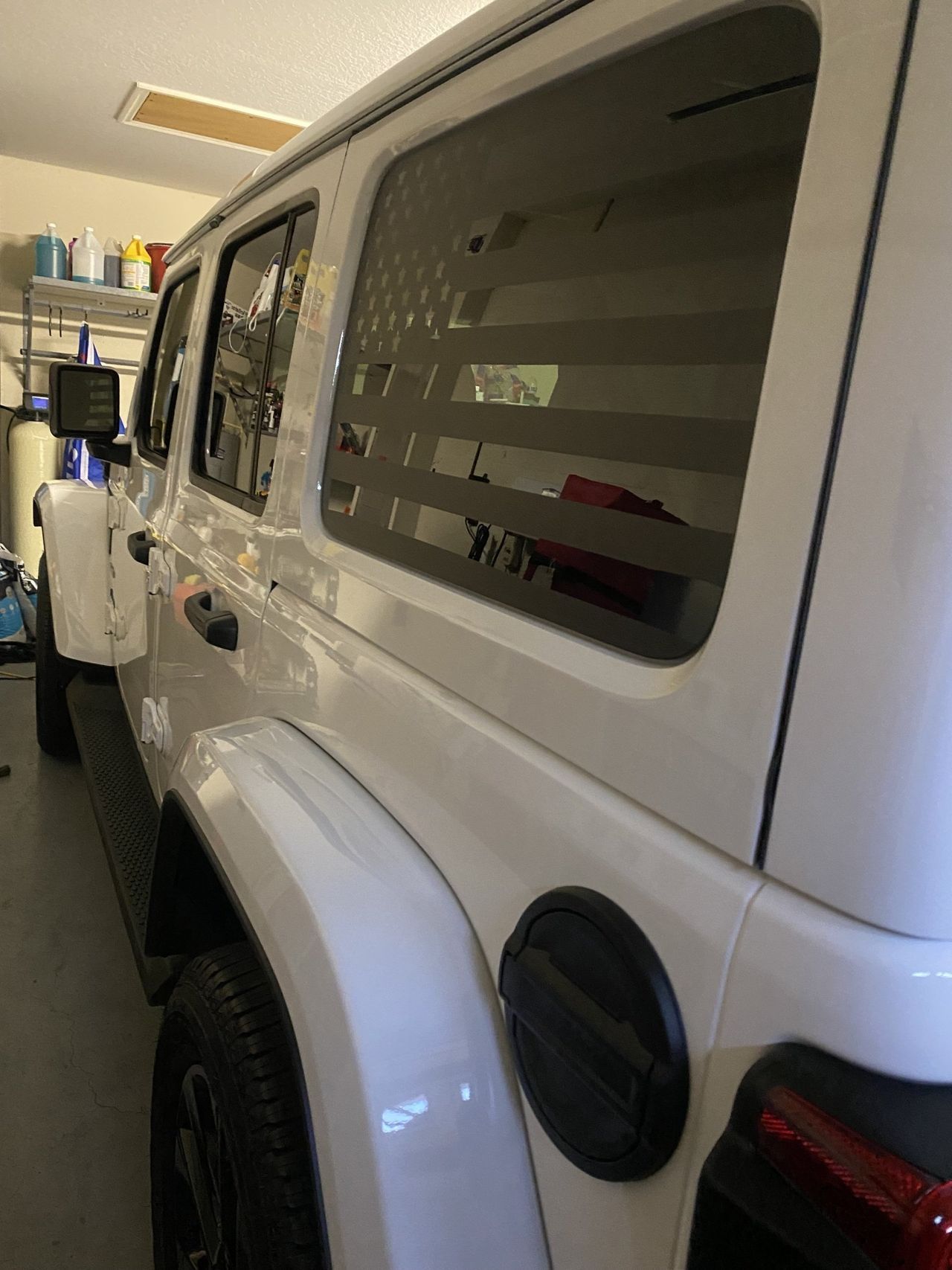 A white jeep wrangler is parked in a garage.