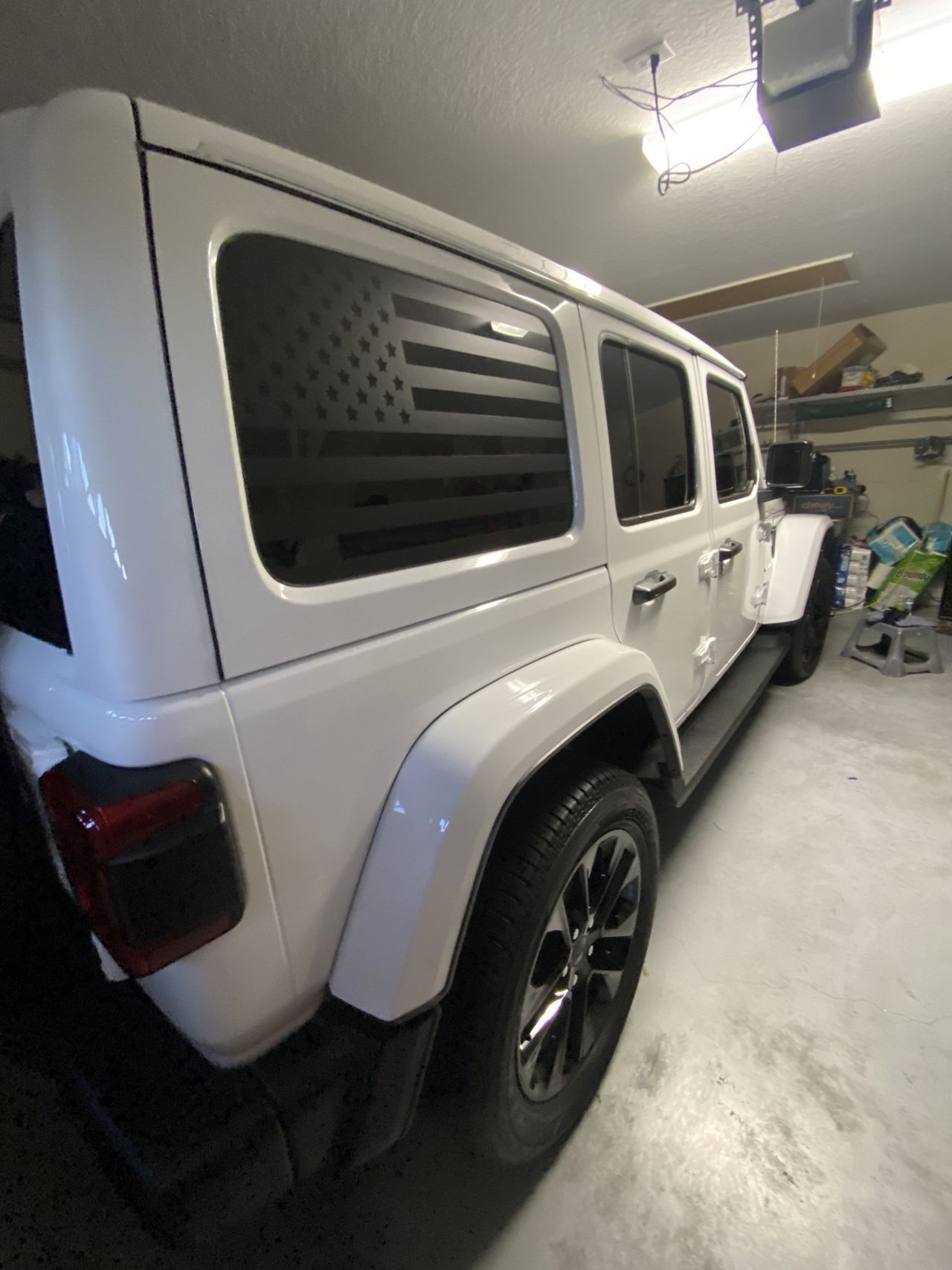 A white jeep wrangler is parked in a garage.