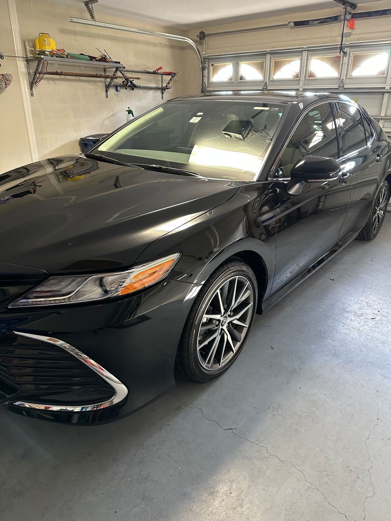 A black car is parked in a garage next to a garage door.