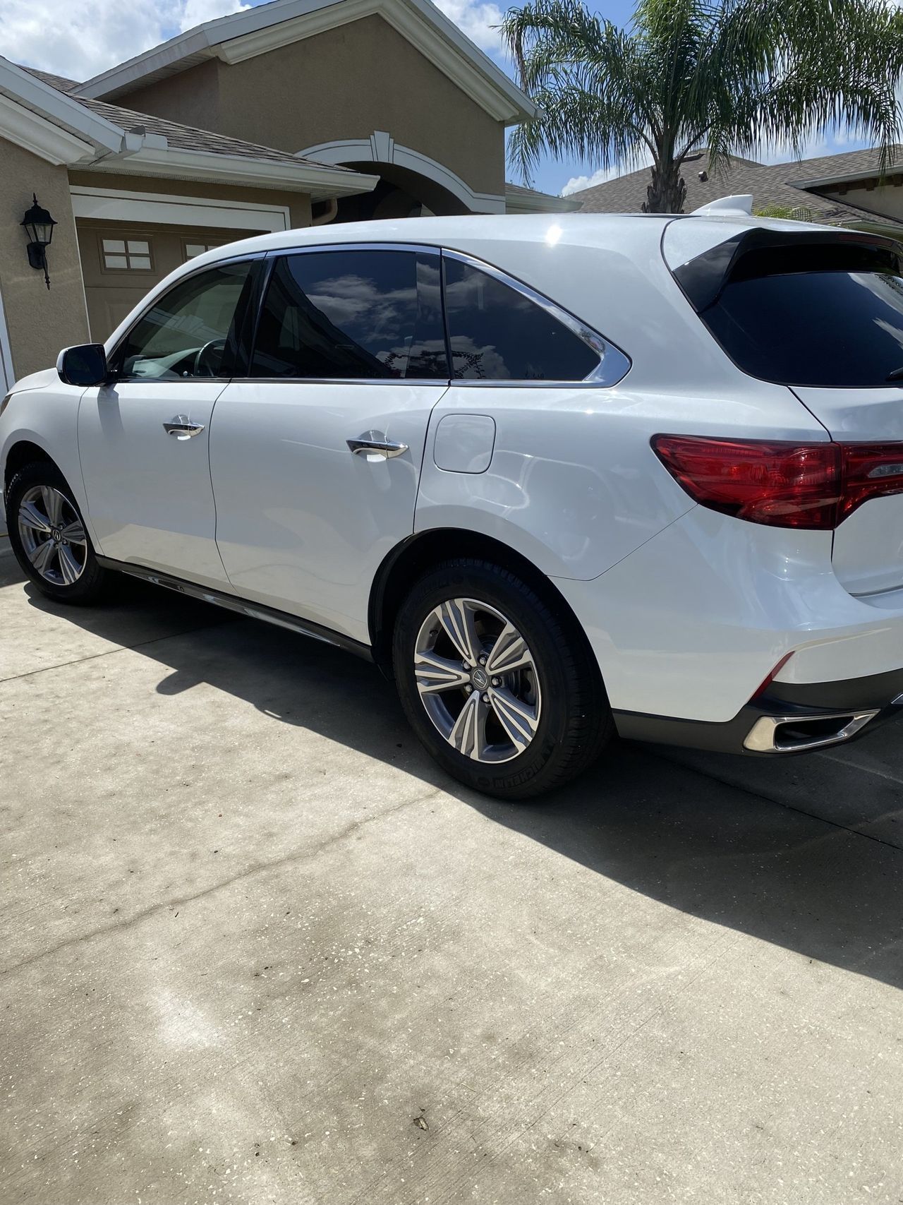 A white suv is parked in a driveway in front of a house.