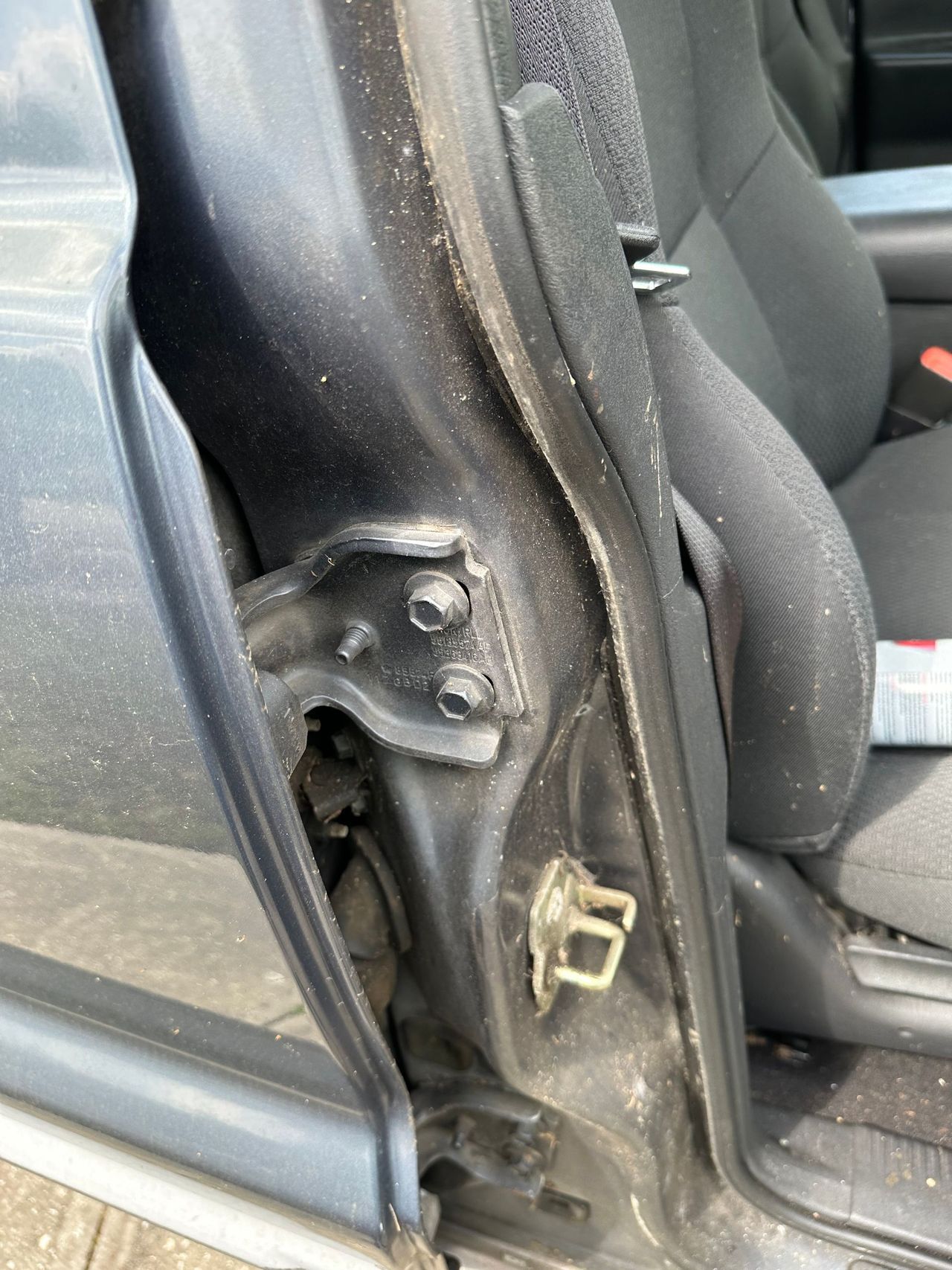 A close up of a car door with a seat belt on it.