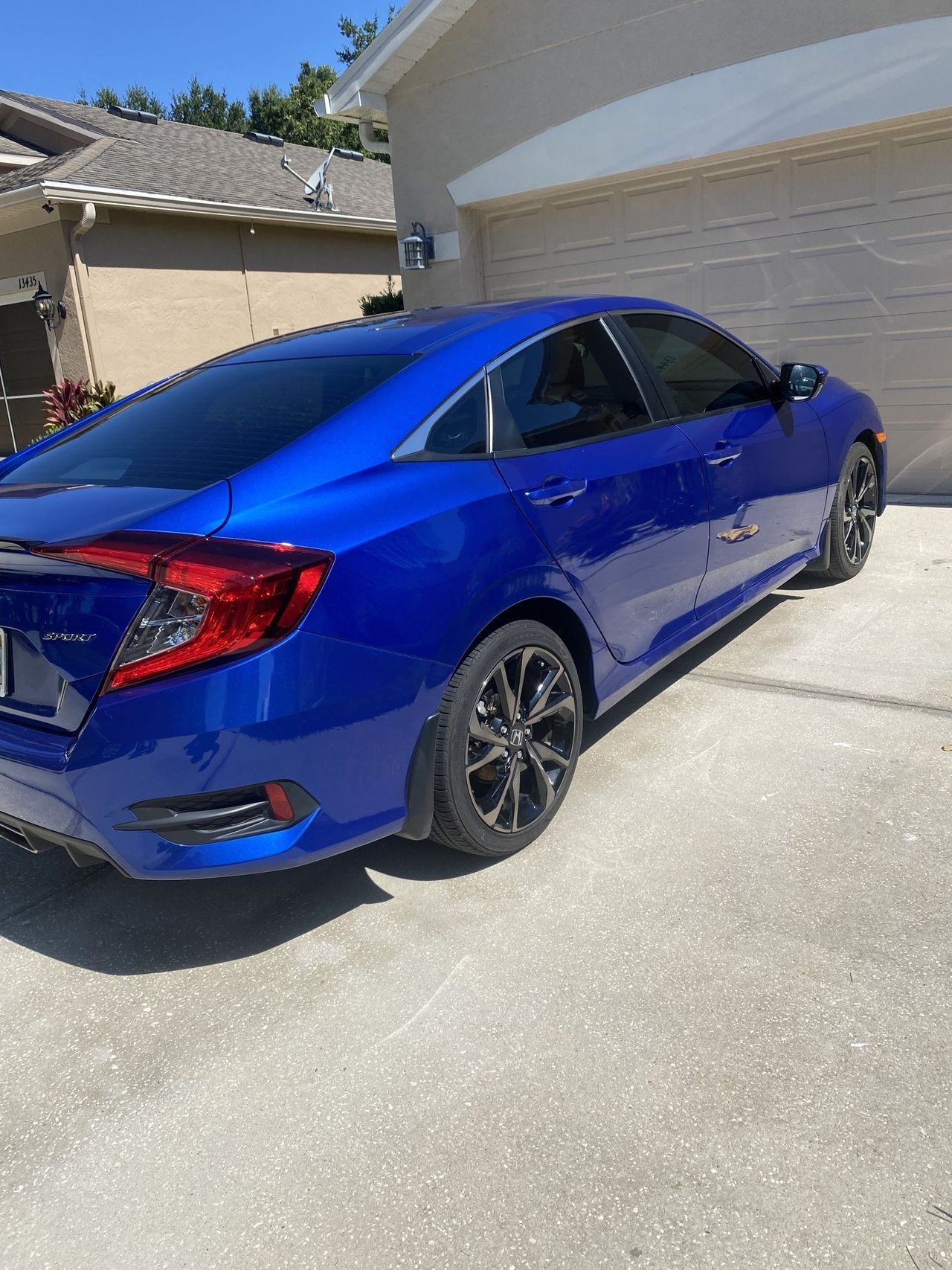 A blue car is parked in front of a garage door.