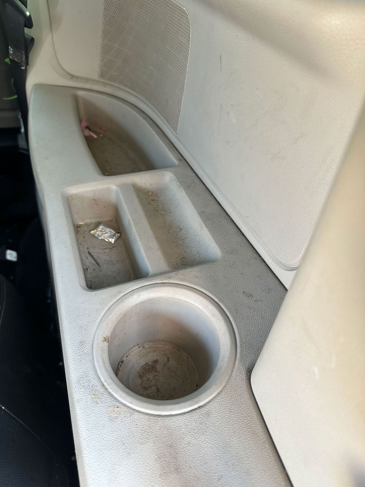 A dirty cup holder in the back of a car