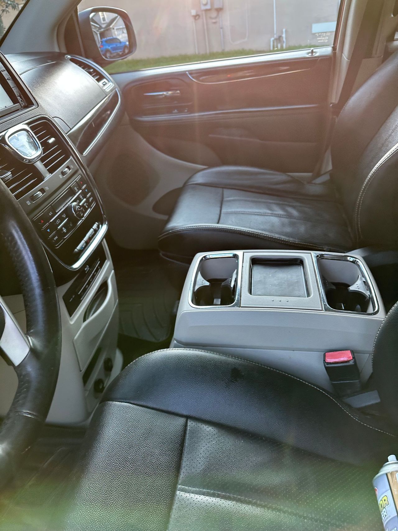 The interior of a minivan with a steering wheel and a cup holder.