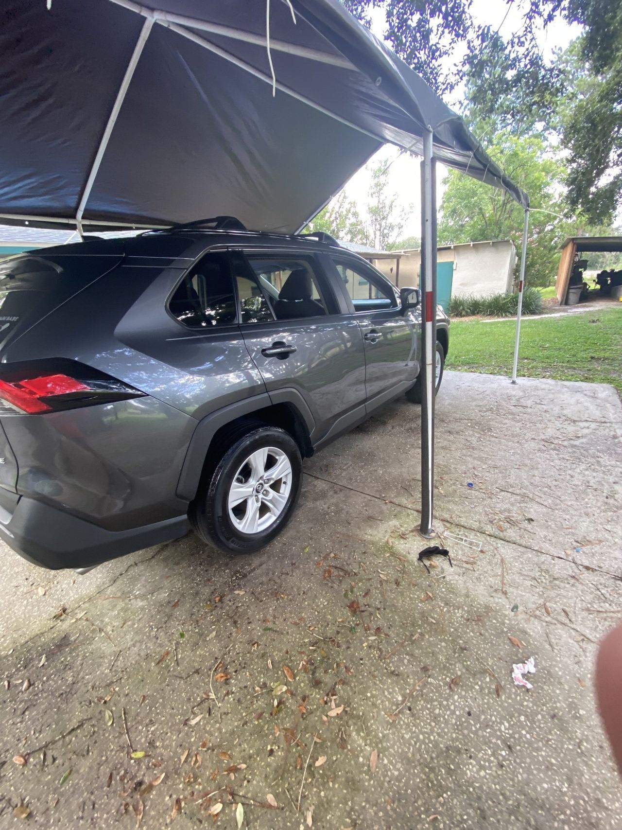 A car is parked under a tent in a parking lot.