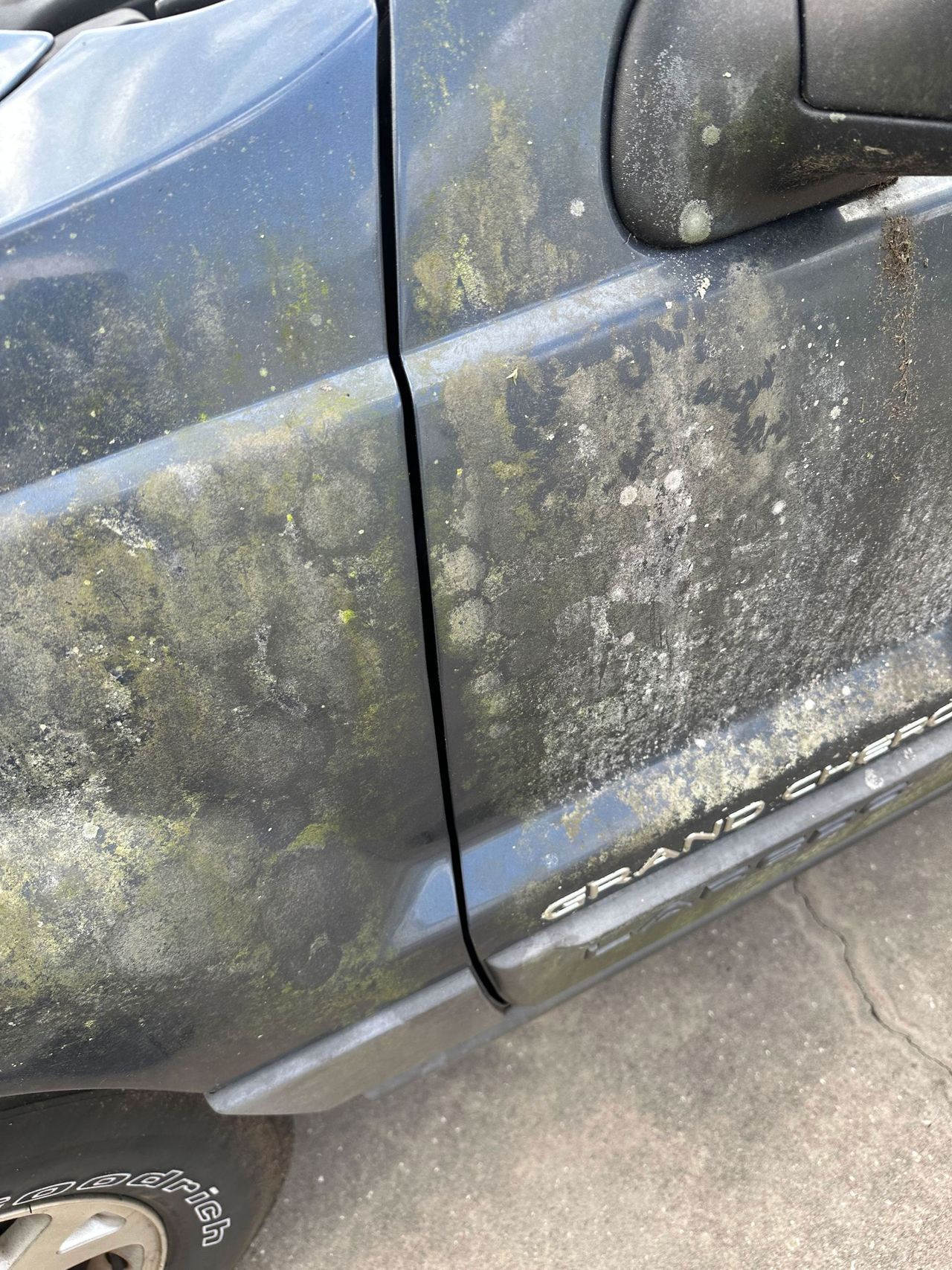 A dirty car is sitting on the side of the road.