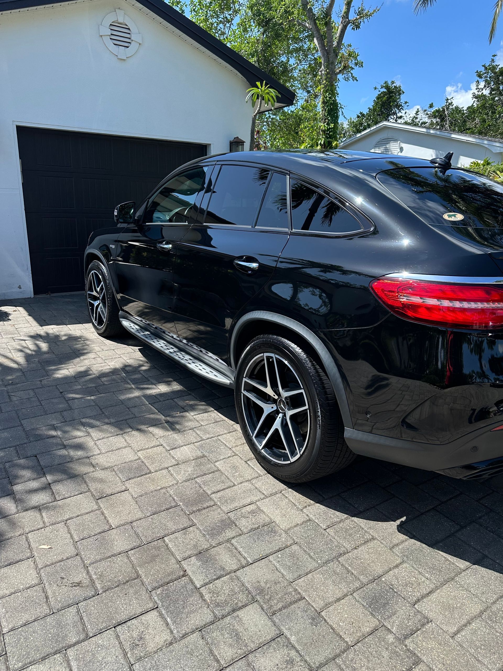 A black car is parked in front of a garage.