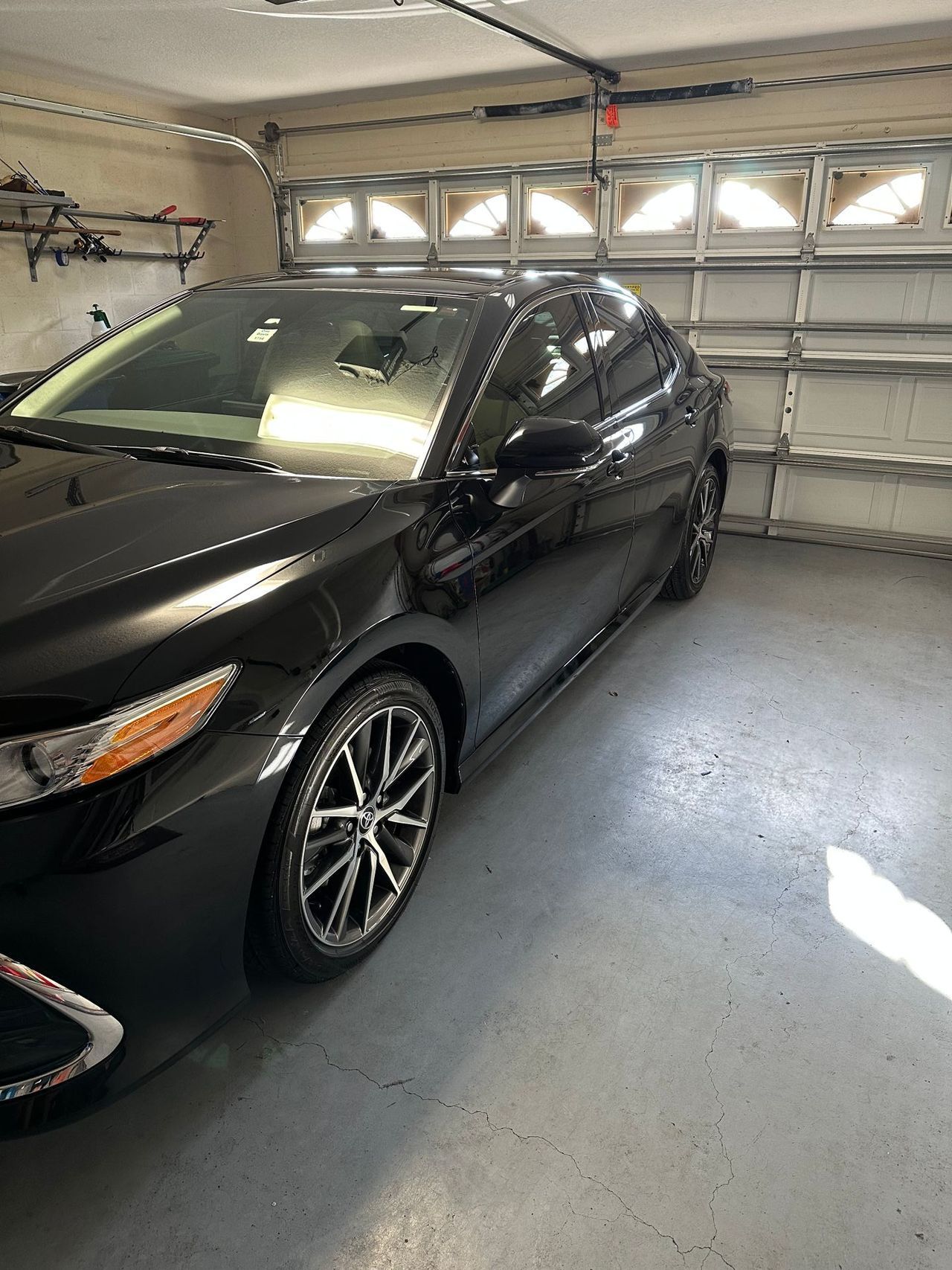 A black car is parked in a garage next to a garage door.