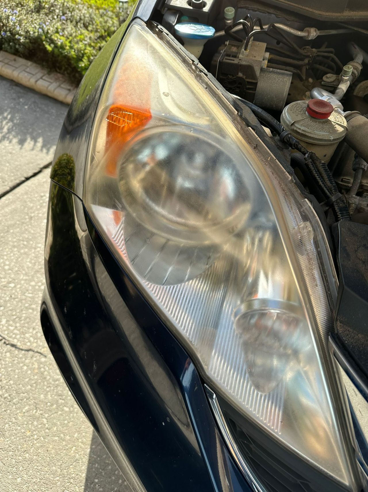 A close up of a car headlight with the hood open.