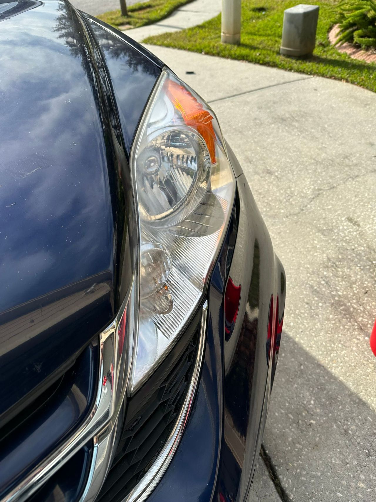 A close up of a car 's headlight on a sidewalk