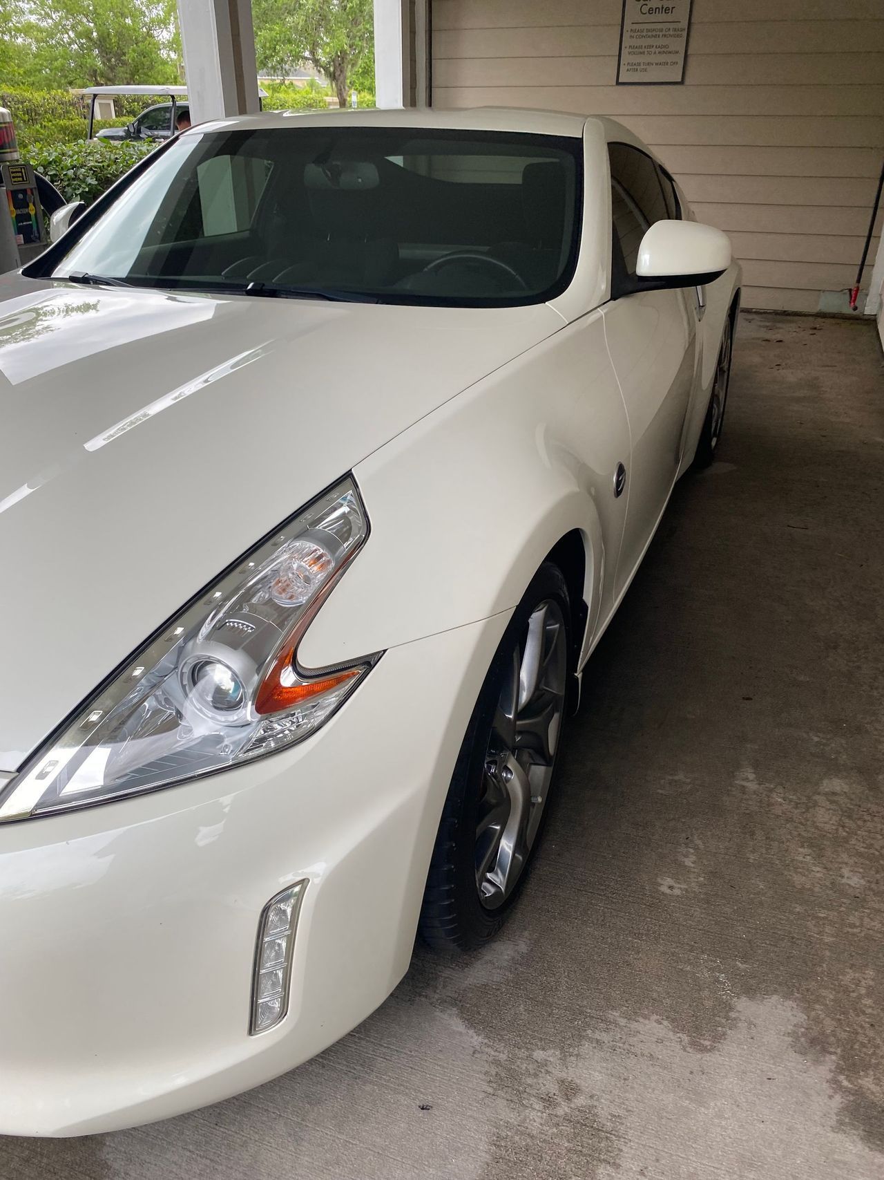 A white nissan 370z is parked in a garage.