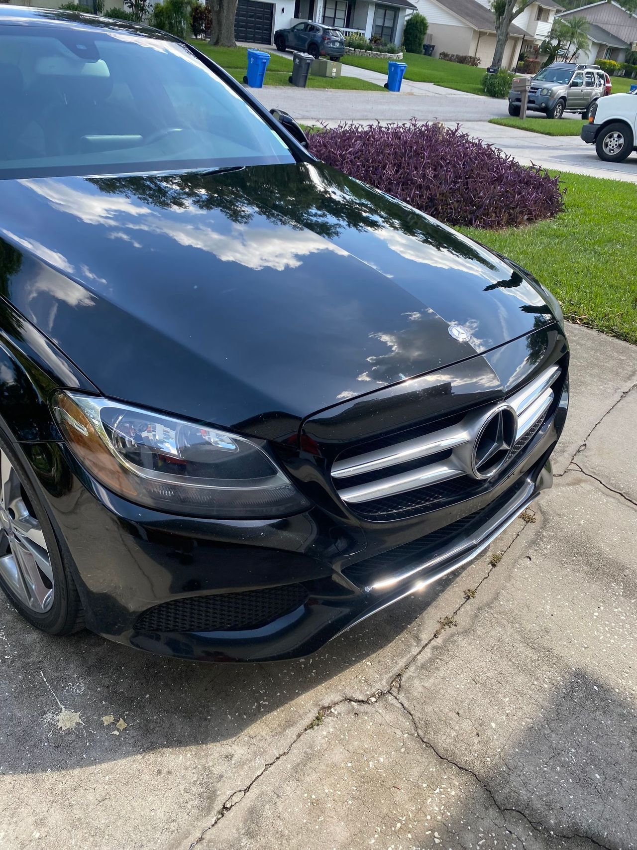A black mercedes benz is parked on the side of the road in a driveway.
