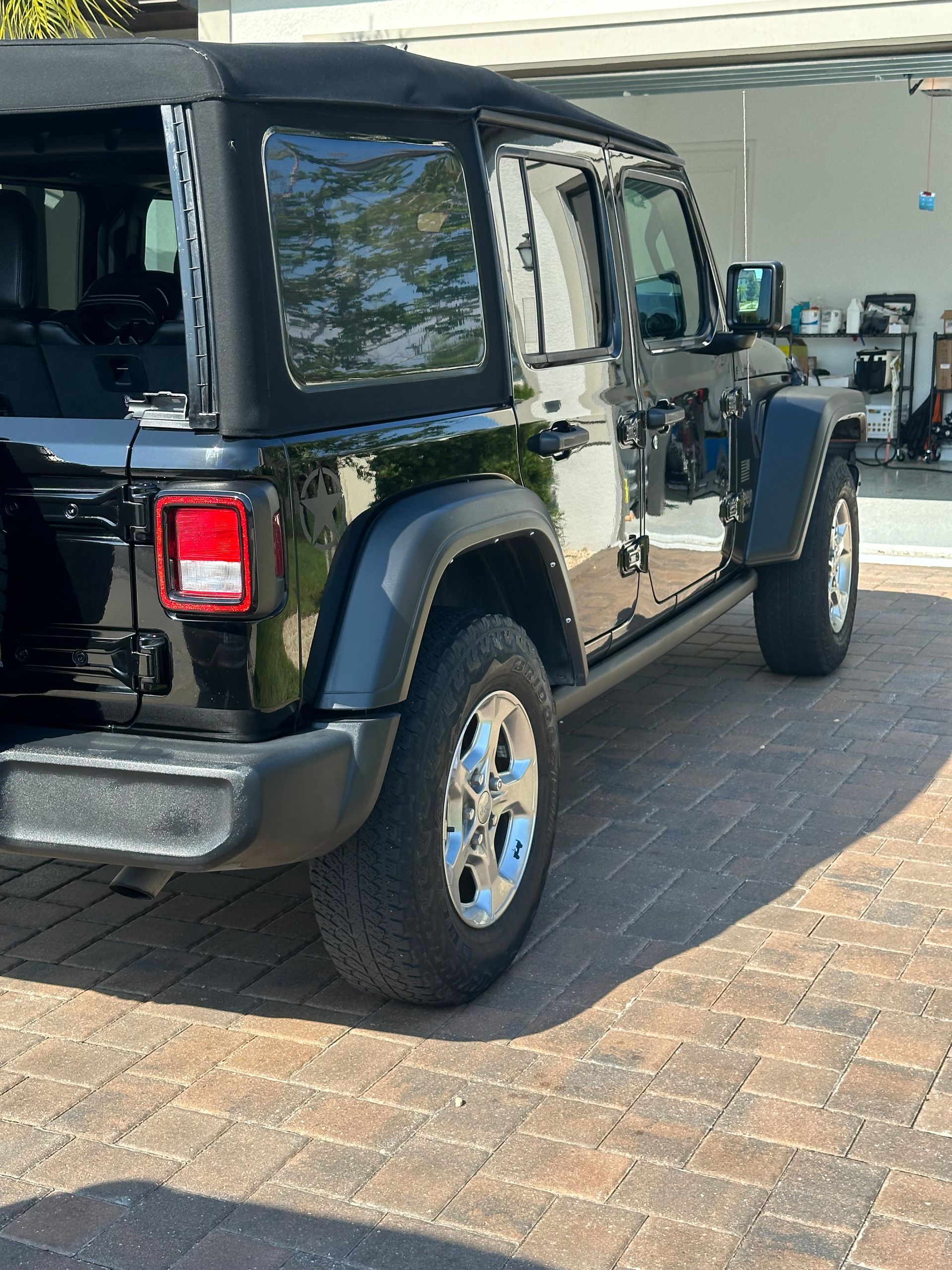 A black jeep is parked in a driveway next to a garage.
