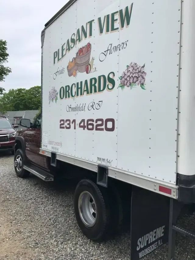 A pleasant view orchards truck is parked in a gravel lot