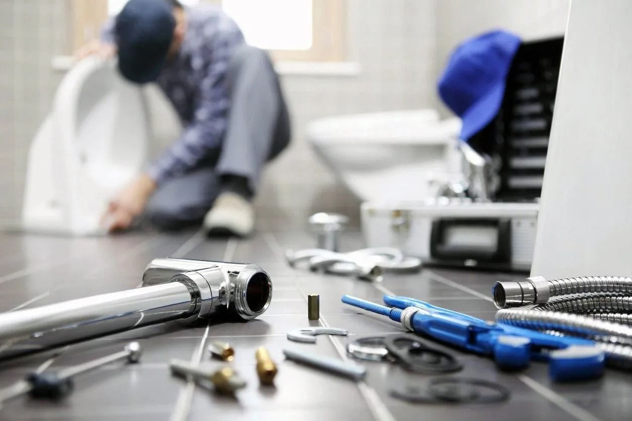 Plumber working on a toilet with tools and equipment in a bathroom.