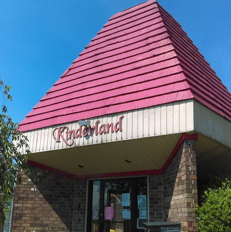 A brick building with a pink roof that says kinderland