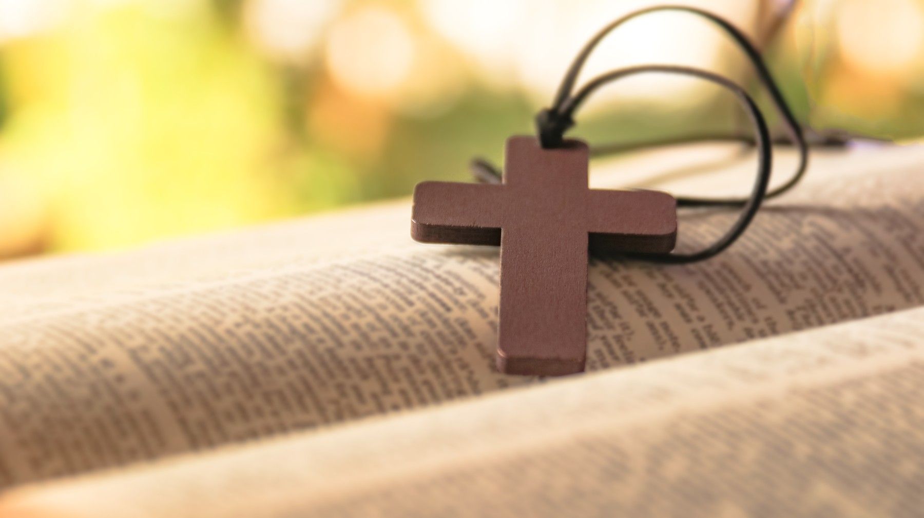 A wooden cross is sitting on top of an open bible.