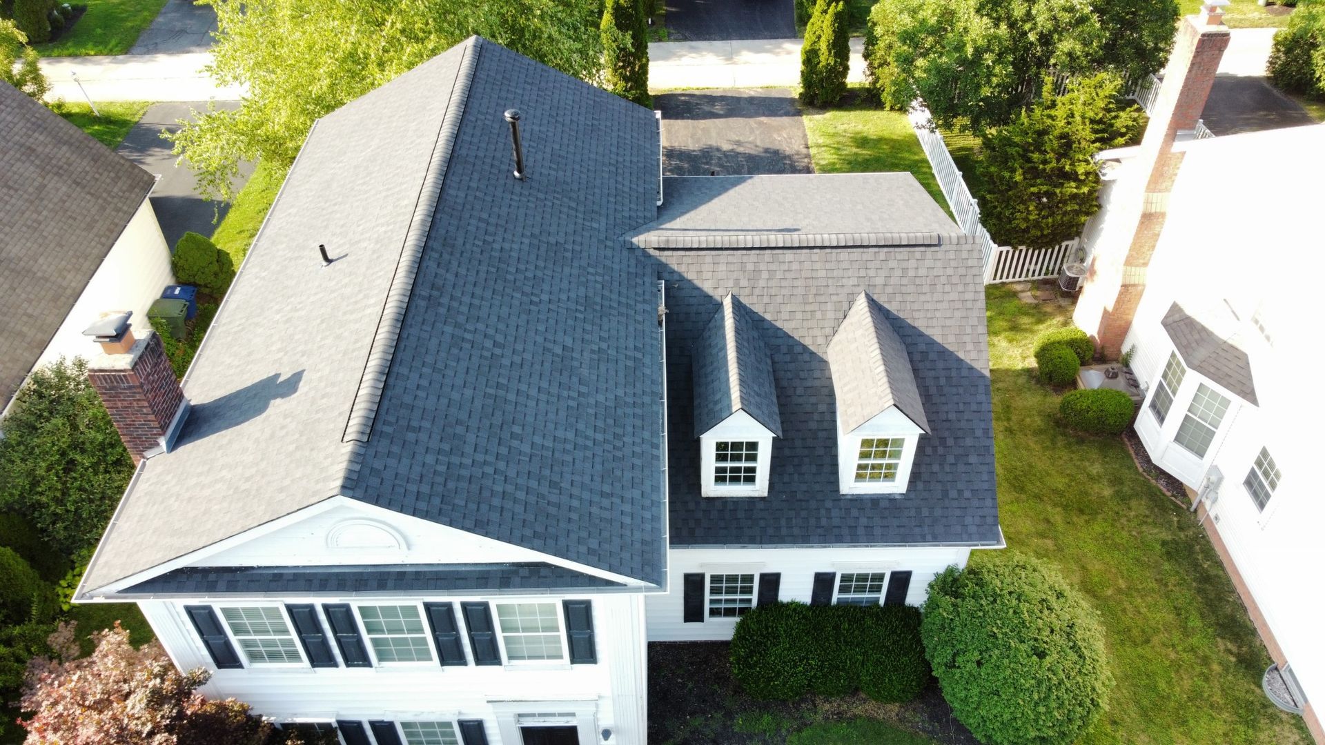 White two-story house with black shutters and a dark gray roof, overhead shot.