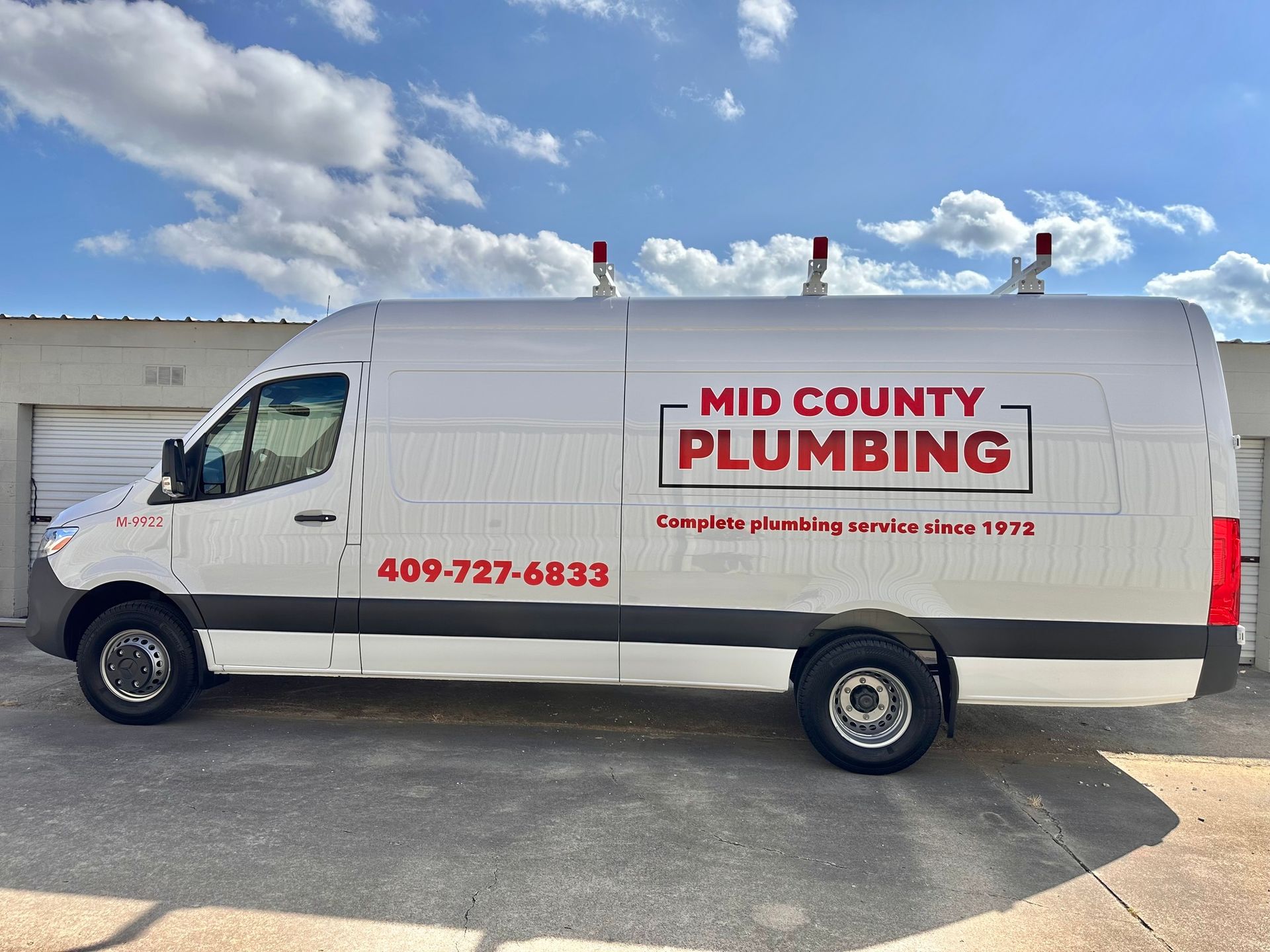 A mid county plumbing van is parked in front of a building.