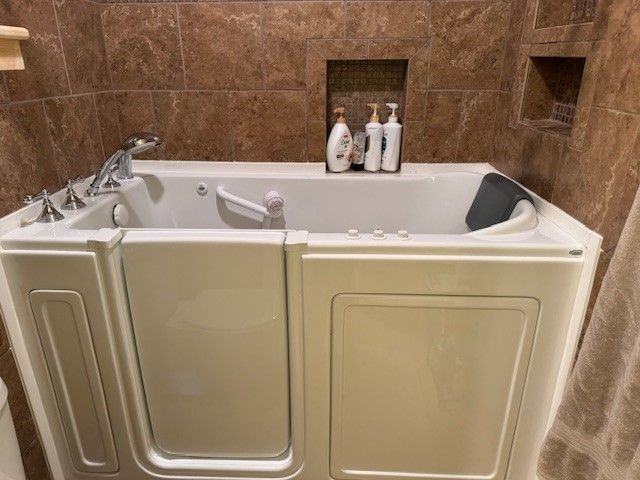 A walk in tub with a door in a bathroom.