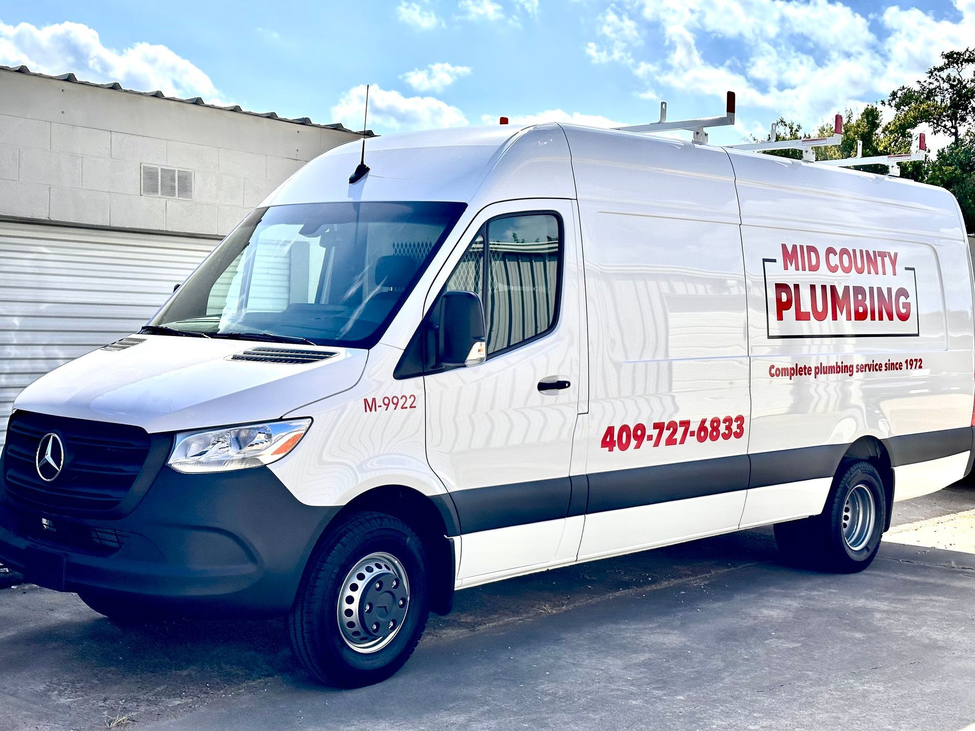 A white van for mid county plumbing is parked in front of a building.