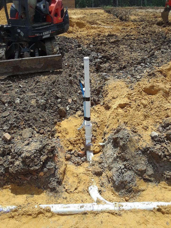 A white pipe is sitting in the dirt next to a bulldozer.
