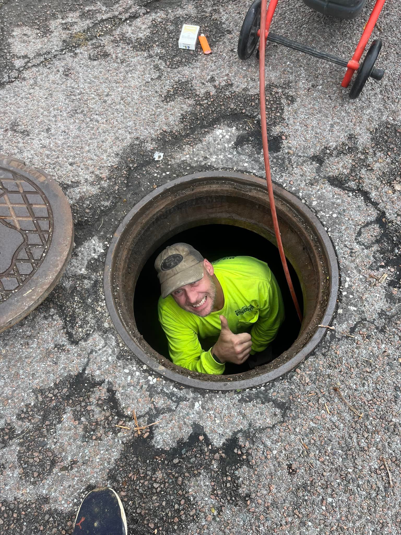 A man is sticking his head out of a manhole cover.