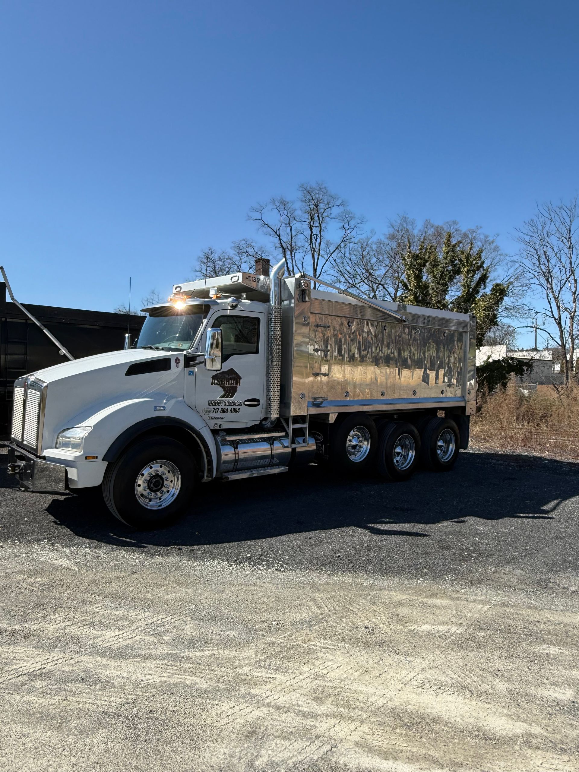 A dump truck is parked in a gravel lot.
