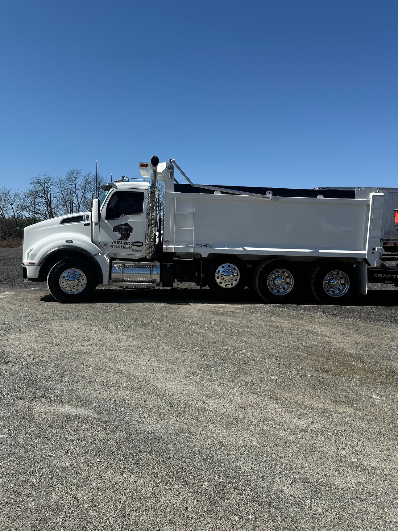 A white dump truck is parked in a gravel lot.