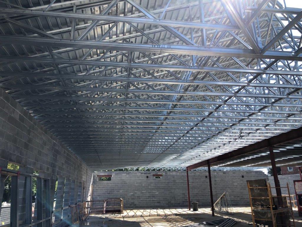 A large metal structure is being built in a building under construction.